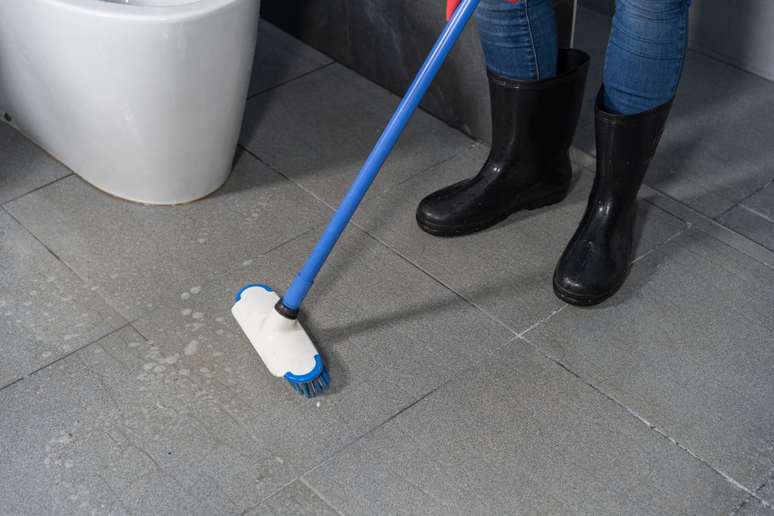 using brush to cleaning the tile in the bathroom