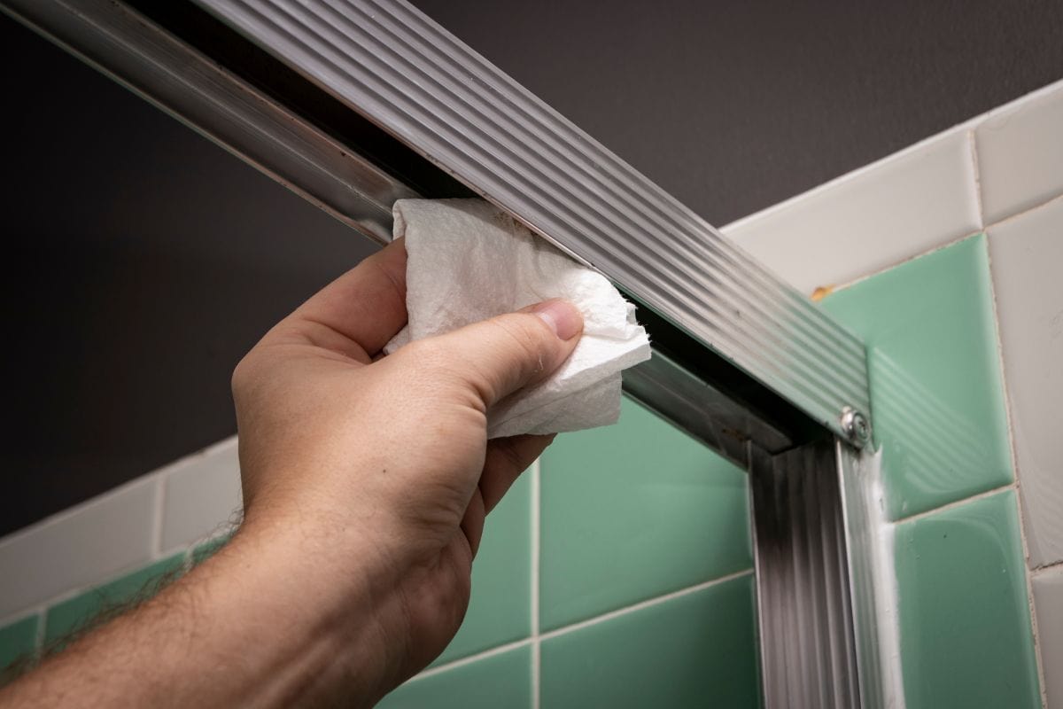 Hand wipes sliding shower door track with towel