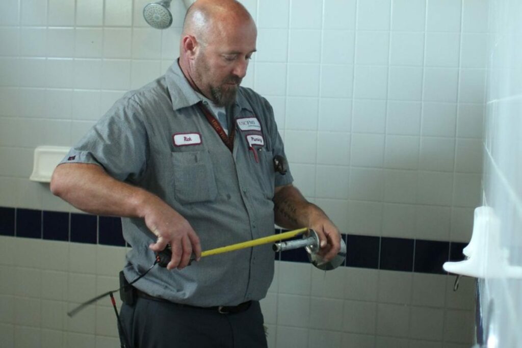 a plumber measuring the dimensions of shower parts