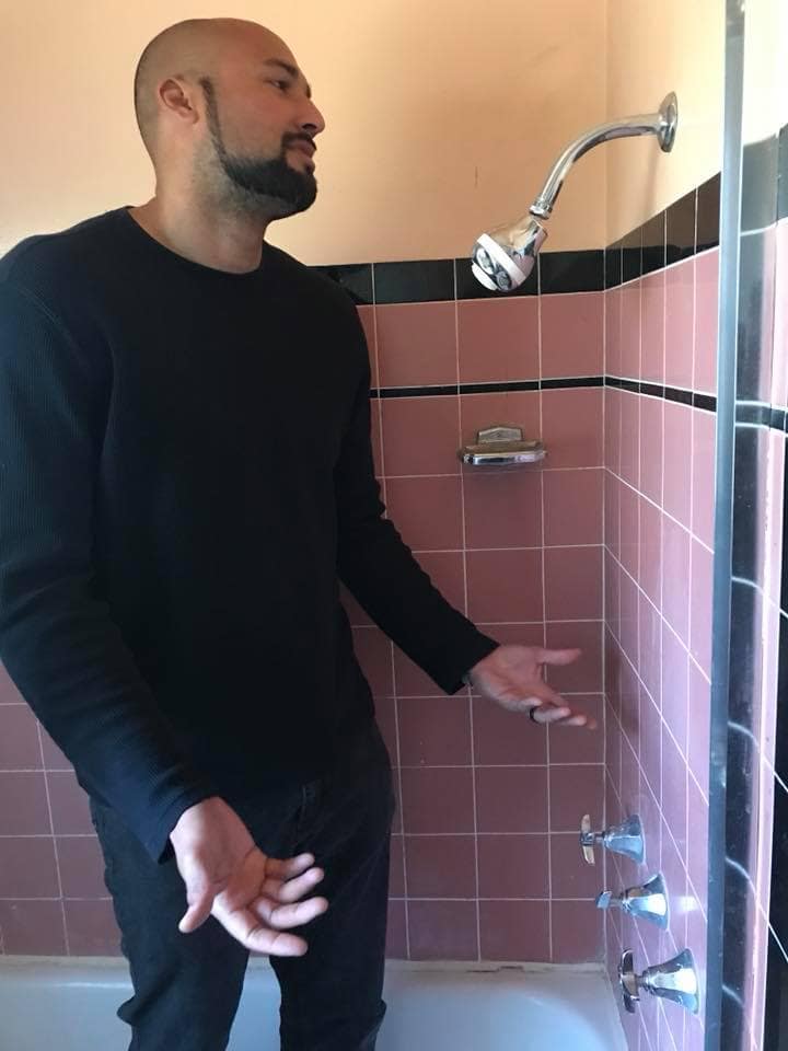 a man is resigned about a low shower head that is even lower than his height