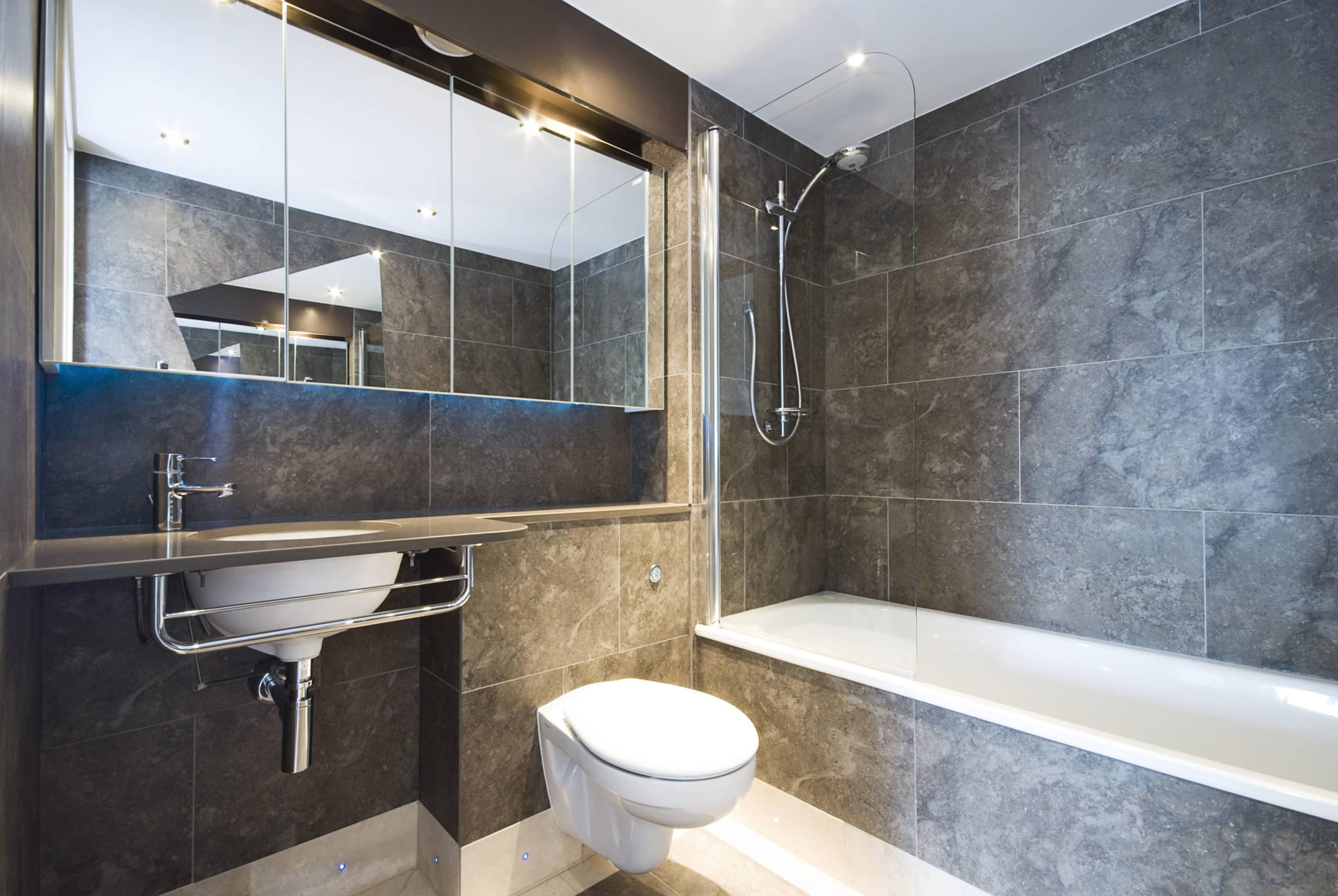 Contemporary en-suite bathroom with natural stone tiles and marble fragments in cappuccino brown