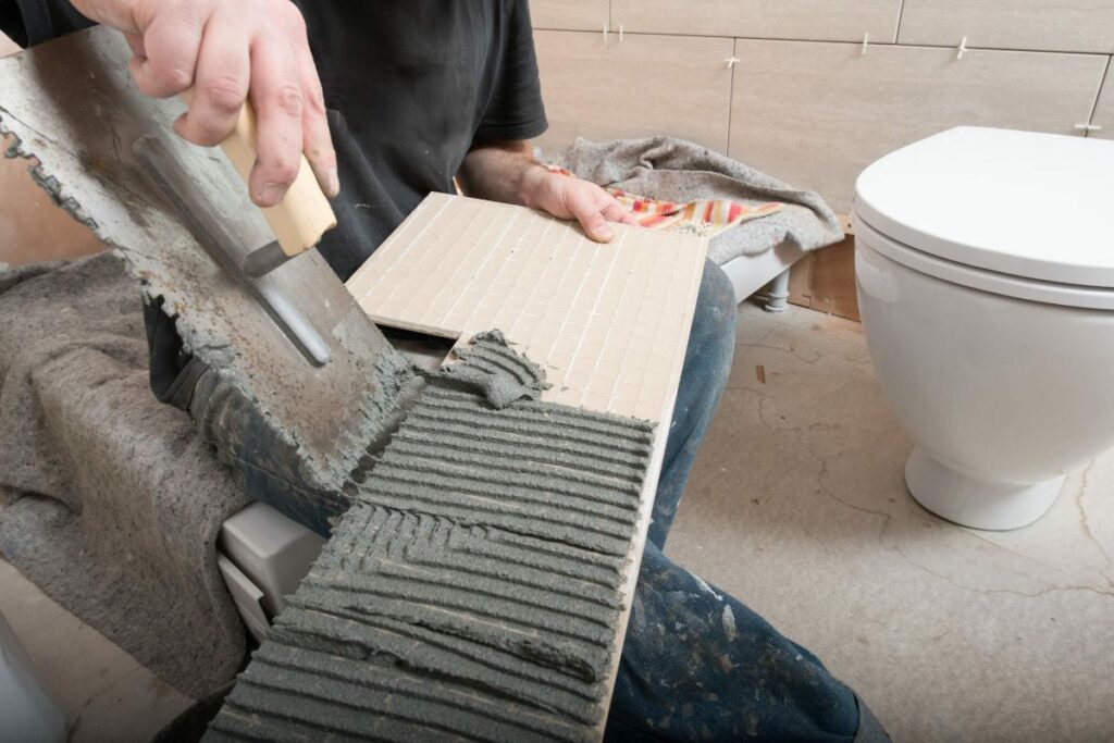 a tiler is ready to install a tile on bathroom floor