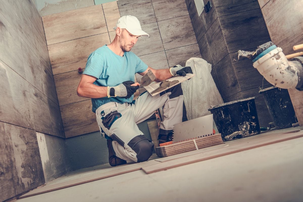 industrial tiler builder worker installing floor tile in a bathroom