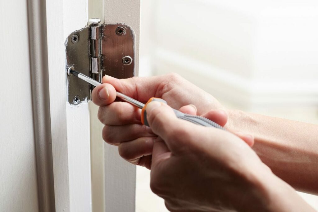 a man is tightening the screw on shower door hinge
