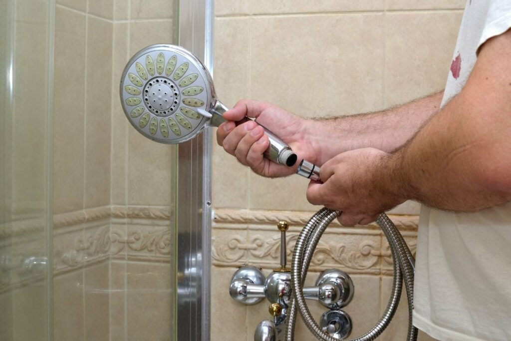 a man is instaling a new shower head, attaching it to the shower valve