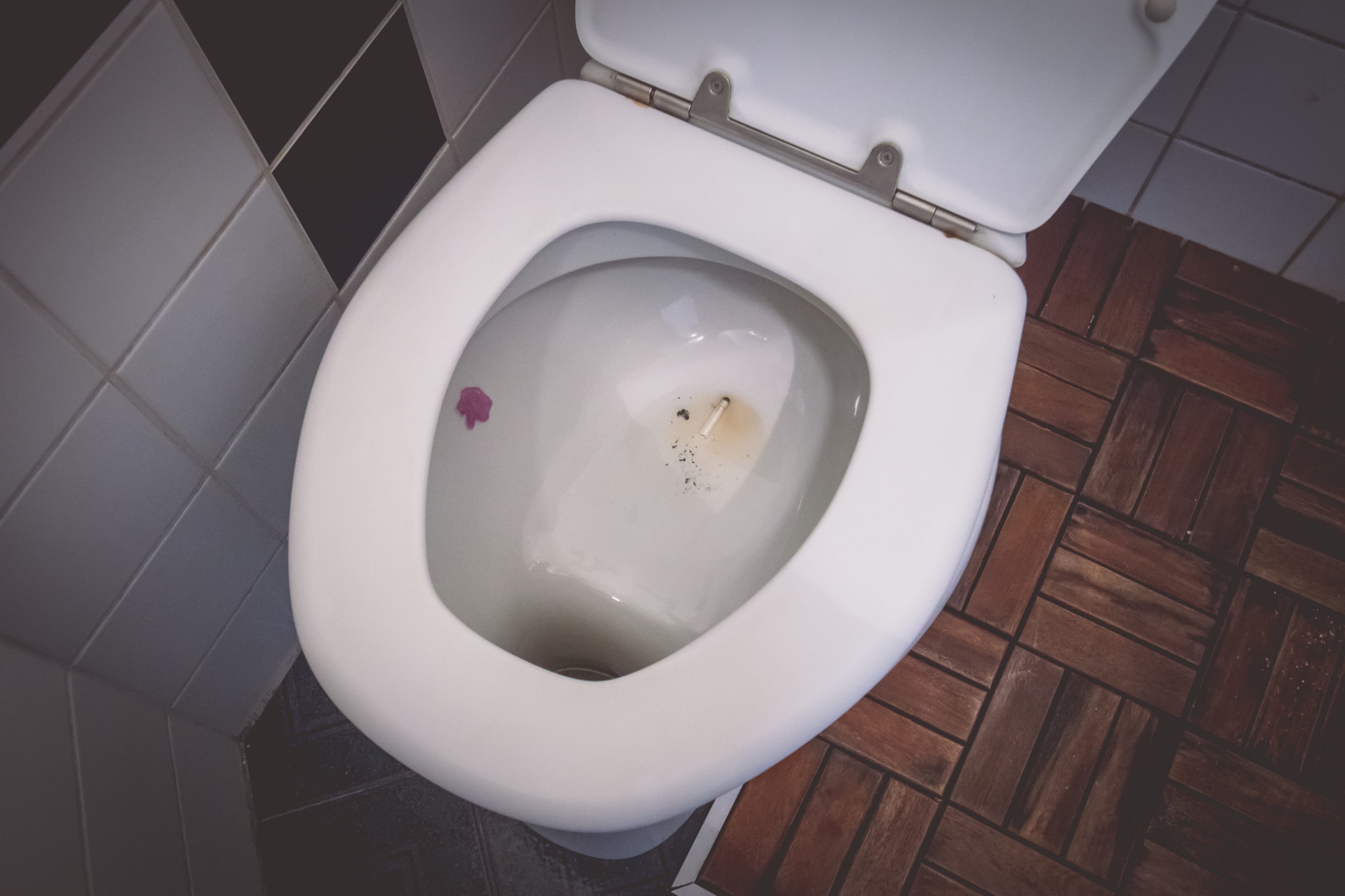 Cigarette butt in a toilet bowl. Cigarette turned down in a bowl of a toilet. Dirty small toilet
