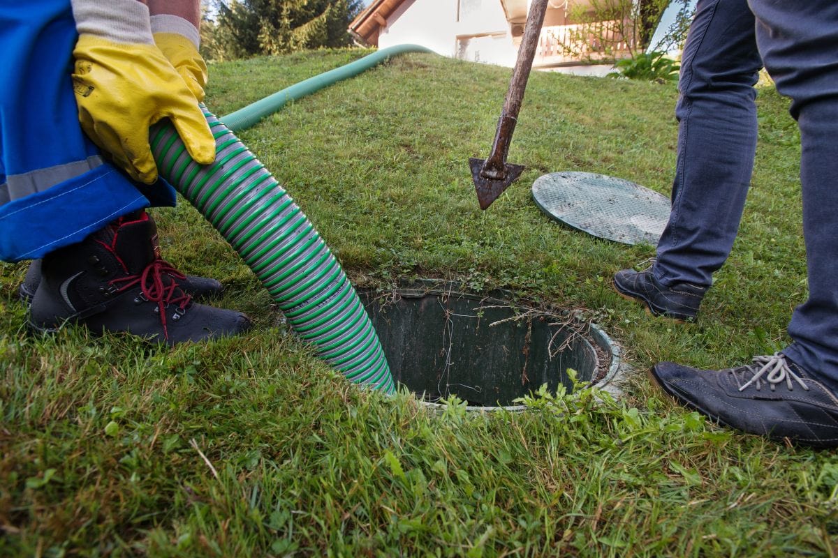 man pumping out house septic tank. drain and sewage cleaning service.